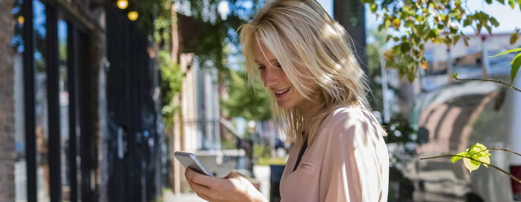 a woman on a sidewalk looking at a cell phone